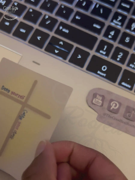 Clip peeling sticker from backing and placing on laptop. Sticker features a cross and the text Deny yourself, carry your cross.