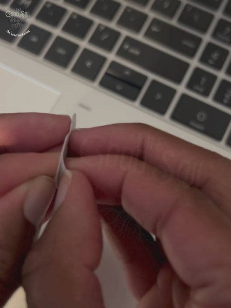 Short clip of hands peeling Colorful 'Surrender' vinyl sticker with pink and blue ombre underline, placing it on laptop.